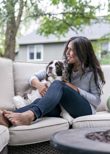 Woman holding her English springer spaniel on a couch in a living room. 