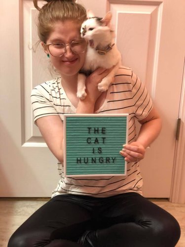 cat poses in front of funny letter board