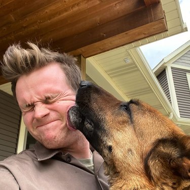 Dog licking a UPS driver's face.