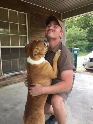 Dog hugging a UPS driver.