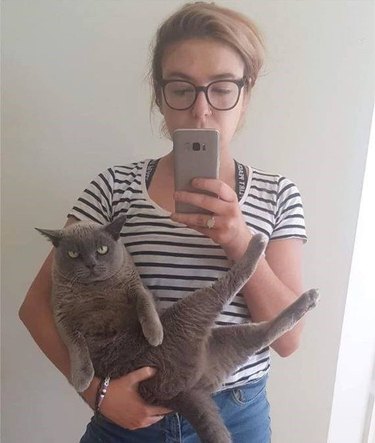 woman takes selfie with scowling cat