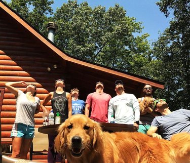 Dog photobombing picture of humans looking up at the sky.