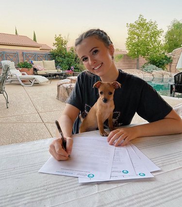 woman signs adoption paper for dog