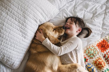 Girl lying on a bed with her golden retriever dog