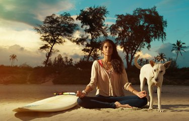 Indian surfer girl meditating in lotus pose