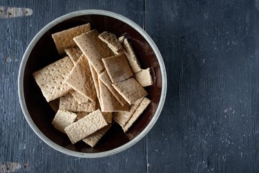 graham crackers in mixing bowl on dark wood table