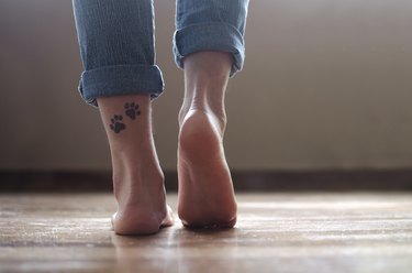 Close-up of a girl's ankles with a tattoo of dog paws