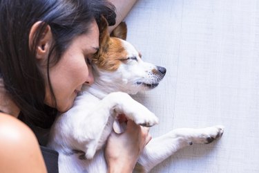 woman cuddling small dog looking happy