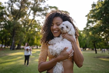 Joyful Latin American woman hugging her dog