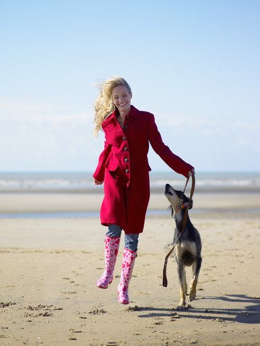 Woman skipping with dog on beach