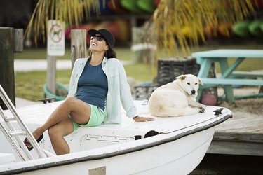 Woman sitting with dog on motorboat