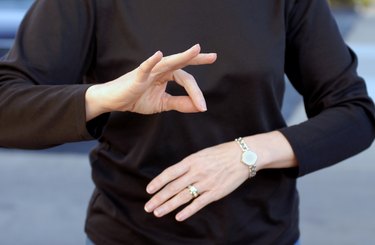 A woman using sign language wearing a black shirt