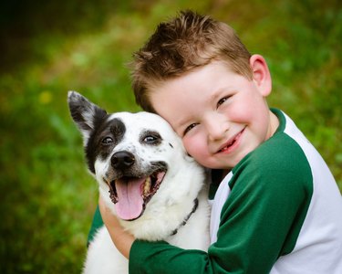 Child lovingly embraces his pet dog
