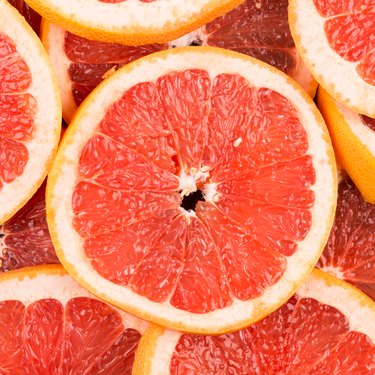 Abstract red background with citrus-fruit of grapefruit slices. Close-up