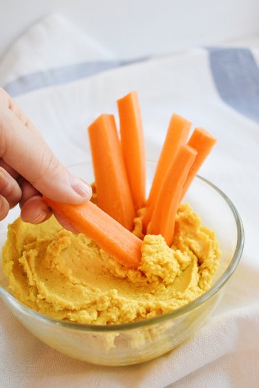 Hummus with carrot sticks being dipped into it