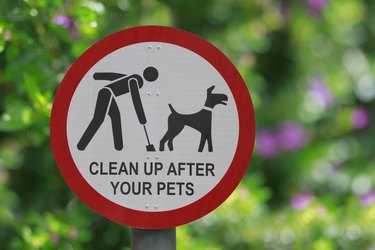 Park sign ("clean up after your pets") in red and white with plants