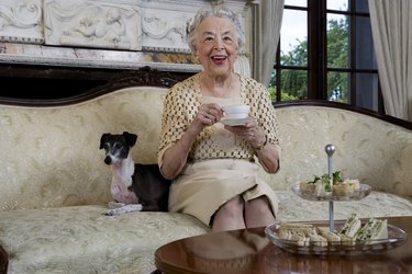Senior woman sitting on sofa with dog, smiling