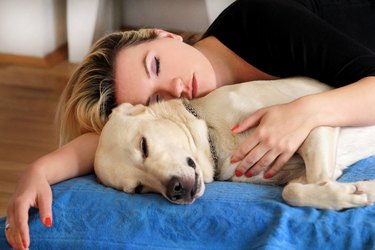 Woman sleeping next to cute dog on bed