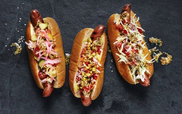 Three gourmet hot dogs on black background