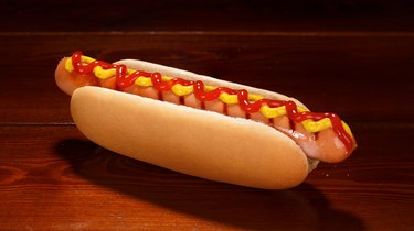 Classic hot dog with ketchup and mustard on a background of wooden boards.