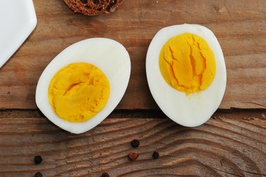 two halves of boiled eggs on wooden rustic background
