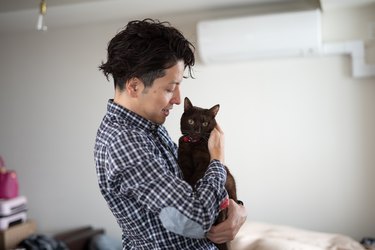 Man embracing cat in sleeping room