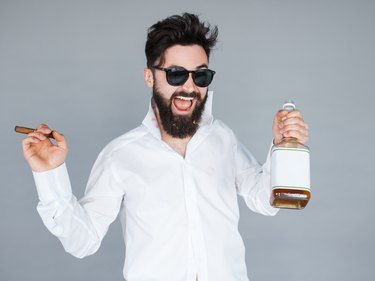man holding a bottle of whiskey and cigar