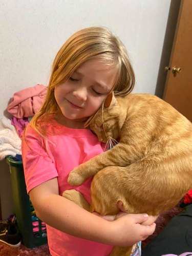 orange tabby cuddles with girl