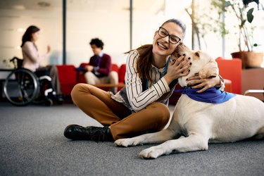 Woman enjoying a therapy dog in an office.