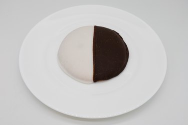 Black and white cookie on a white plate.