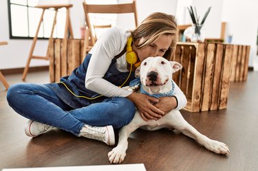 Young caucasian woman smiling confident hugging and kissing dog at art studio