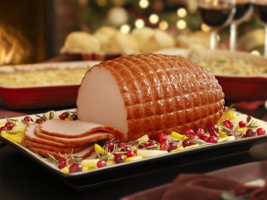Christmas Ham on a table with wine glasses in background