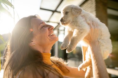 Woman holding small white puppy