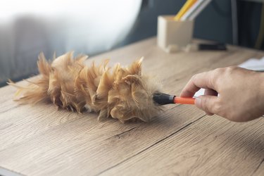 Use a feather duster to clean the table.