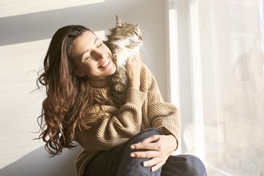 Brunette female in knitted sweater with her fluffy cat.