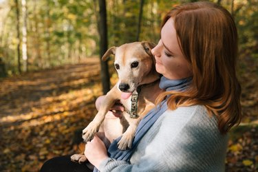 Young redheaded woman hugs her mixed-breed dog