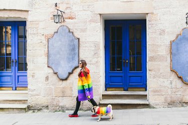 Young woman and her dog enjoying the great city walking in rainbow clothing