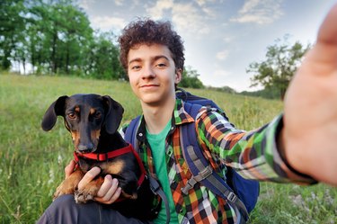 Boy with his dog making selfie at the walk