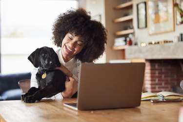 Shot of a young woman playing with her dog at home