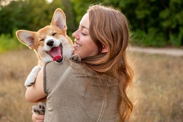 woman holds smiling corgi