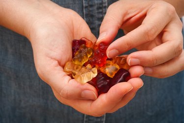 Woman hand taking Gummy bear candy from her palm full of gummy candies
