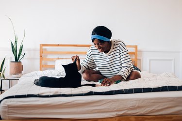 Happy Woman Doing Makeup in the Morning while her Black Cat Keeps her Company