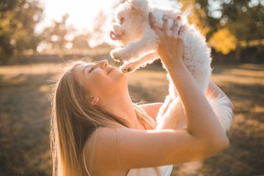 Female dog owner kisses her pet as they stand in the park