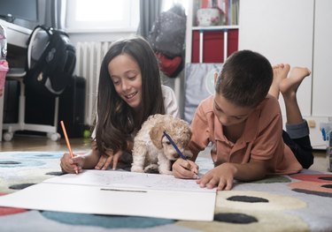 Happy kids with dog at home color the coloring book