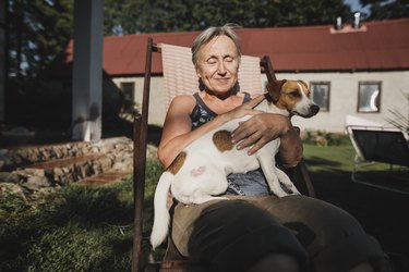 Smiling senior woman with dog on deckchair in garden