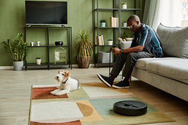 Man using Robot Vacuum Cleaner in Modern Apartment