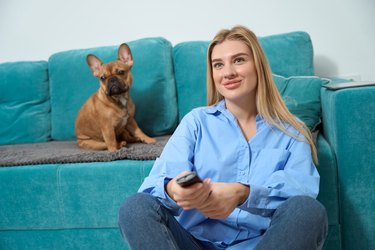 Smiling woman and her four-legged friend watching television