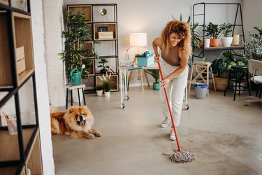 Woman mopping floor while dog watches