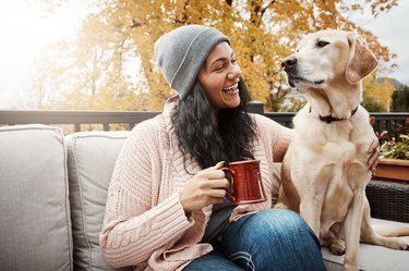A person holding a mug and their dog in Autumn