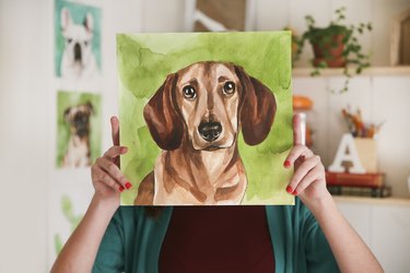 Artist hiding behind aquarelle of a dachshund